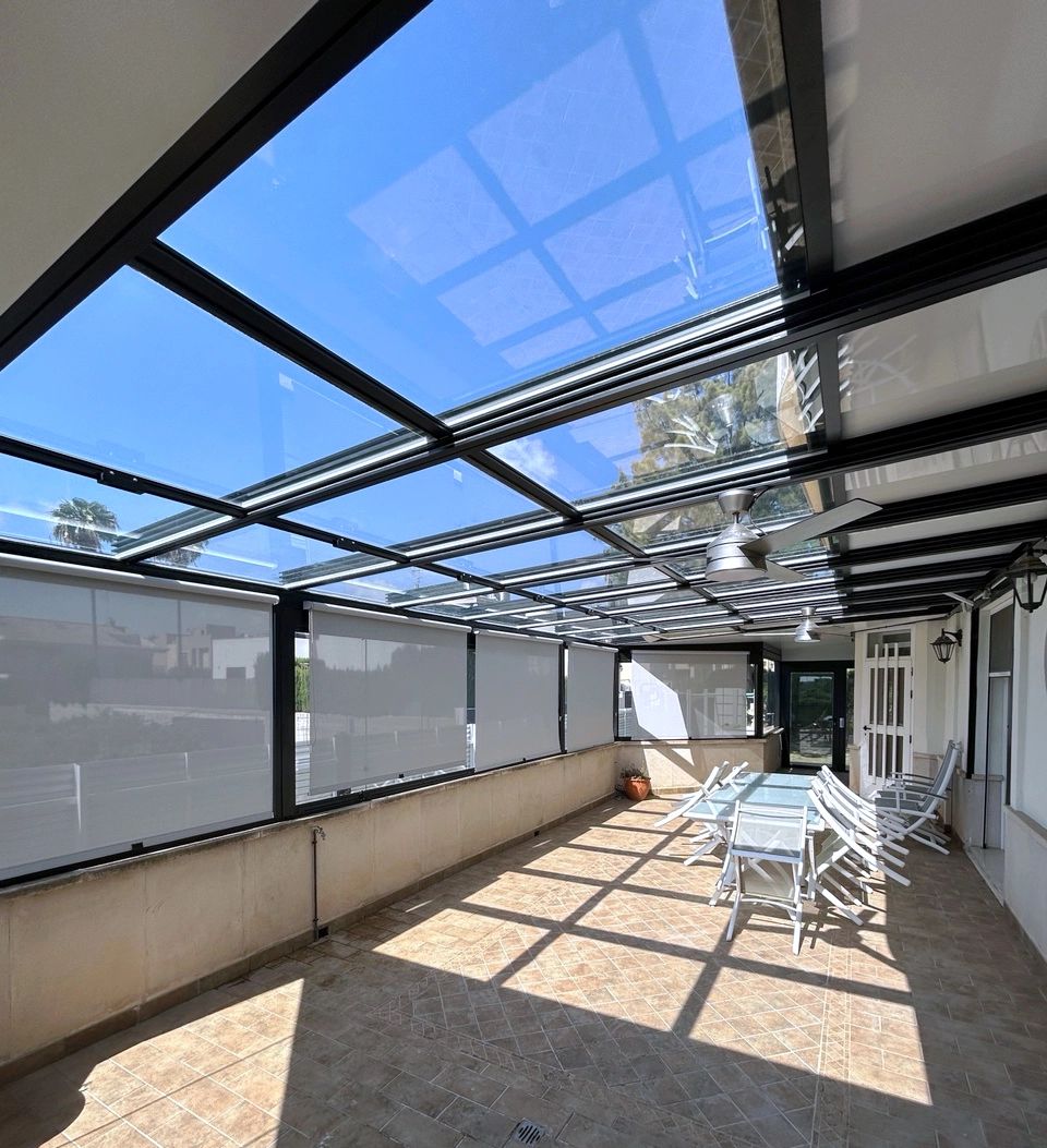 Terraza acristalada con techo corredizo para protección solar.