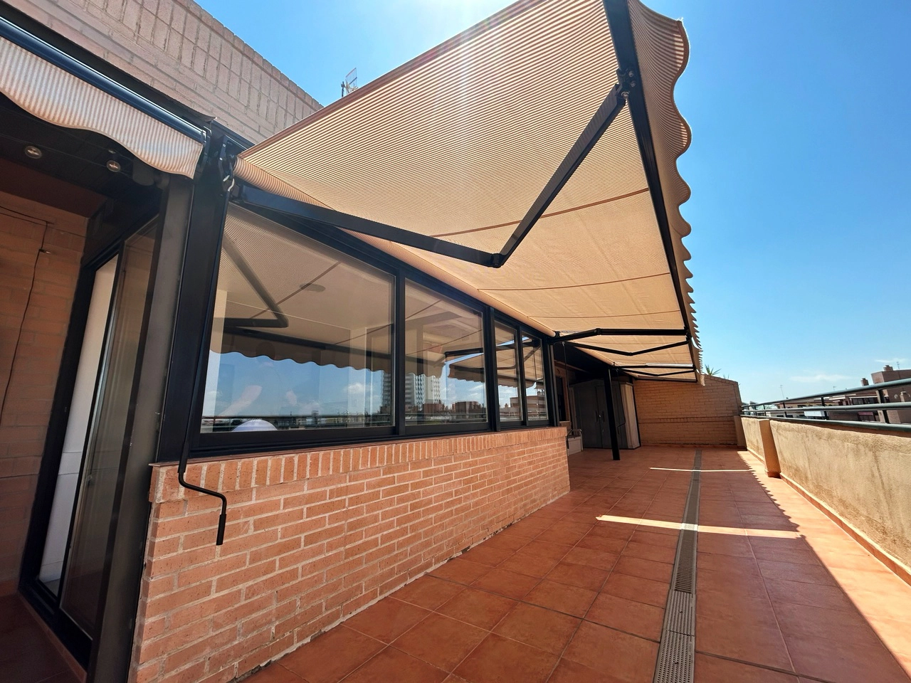 Toldo de tela instalado sobre la parte acristalada de la terraza
